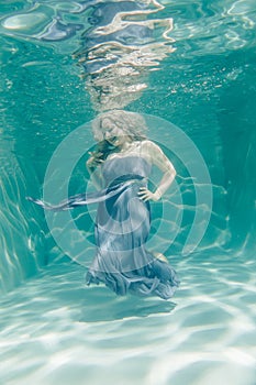 Chubby woman in grey evening long dress swimming underwater on her holidays and enjoy with relax