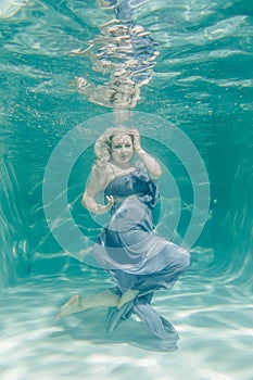 Chubby woman in grey evening long dress swimming underwater on her holidays and enjoy with relax