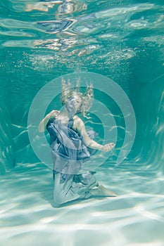 Chubby woman in grey evening long dress swimming underwater on her holidays and enjoy with relax