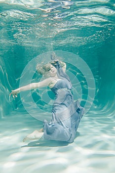 Chubby woman in grey evening long dress swimming underwater on her holidays and enjoy with relax