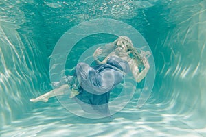 Chubby woman in grey evening long dress swimming underwater on her holidays and enjoy with relax