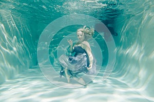 Chubby woman in grey evening long dress swimming underwater on her holidays and enjoy with relax