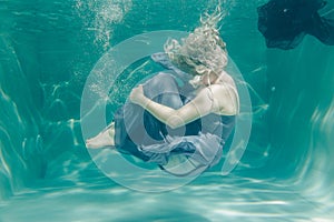 Chubby woman in grey evening long dress swimming underwater on her holidays and enjoy with relax