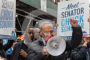 Chuck Schumer standing in front of a crowd, raising a megaphone and talking to them