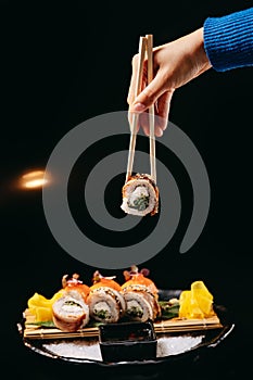 Chuka Roll in Chinese chopsticks in hand on a black background