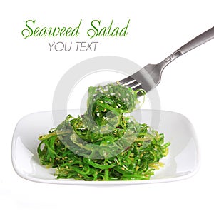 Chuka salad. Seaweed with sesame seeds on fark and ceramic plate, isolated on white. Japanese Cuisine