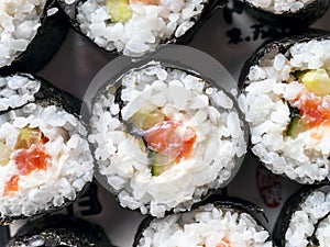 Chumaki Sushi Rolls with Tuna, Salmon, Rice, Cucumber, Avocado And Nori Seaweed on a Plate with Soy Sauce Dipping Dish and