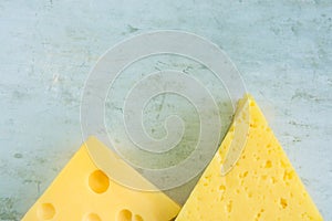 Chunk and Wedge of Alpine Creamy Appetizing Yellow Tilsit and Maasdam Cheese on Scratched Grey Metal Background. Texture