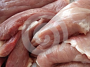 Chunks of meat. Raw pork. Fine veins and texture of the meat. Pink meat with darker red areas. Fresh meat products for sale.