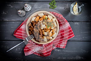 Chunky beef stew with savory sauce beside potato dumplings.