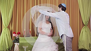 During the chuppah ceremony, the Jewish bride and groom in the synagogue lifts the veil from the bride's face.