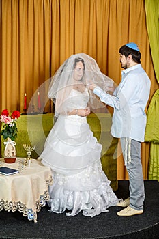 During the chuppah ceremony at a synagogue wedding, the groom covers the bride with a veil in the Badeken ceremony.