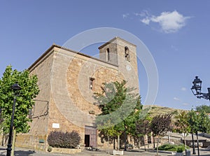 Church of the Assumption in the town of Clavijo with a clock and a green tree in front of it. photo