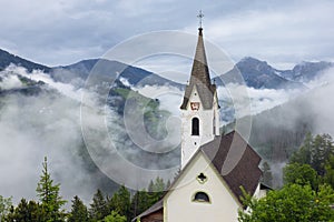 Church on the background of the Italian Alps in the clouds