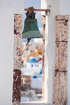 Church bell against churches in Oia village on Santorini island, Greece