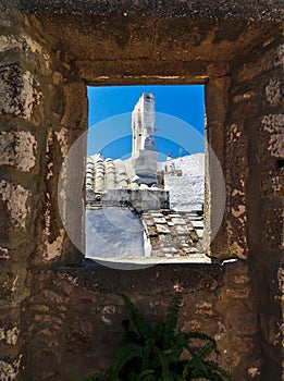 Church bell tower framed by window.