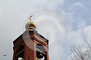 Church bell tower with a Golden dome and a cross against the sky in Russia