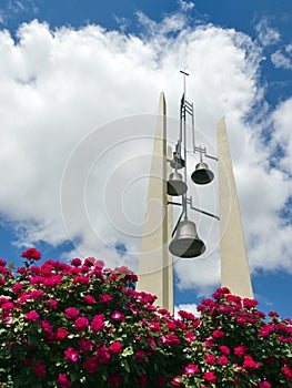 Church Bells Against Bright Blue Sky Clouds and Red Roses