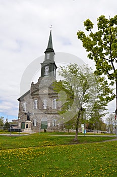 church building with green grass lawn with yellow dandelions