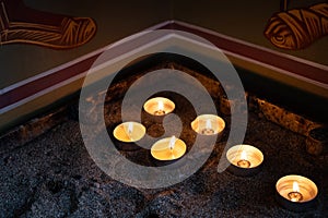 Church candles glowing with orange flames in a temple. Symbols of faith and religion and for wishes and prayers