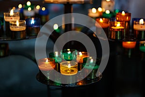 Church candles in red, green, blue and yellow transparent chandeliers