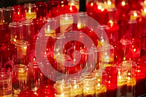 Church candles in red and yellow transparent chandeliers