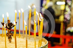 Church candles in the temple against the background of icons and parishioners. Selective focus. Foreground