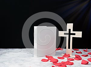 Church composition with wooden cross , bible and red rose petals at a close-up on white background,