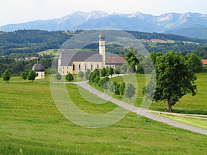 Church in mountainous landscape by green meadows, spring season nature