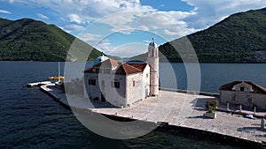 Church of Our Lady on the Rocks with a bell tower on the island of Gospa od Skrpjela. Drone