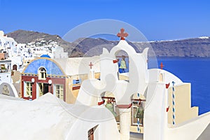 Church with red cross and green bells in Oia village, Santorini