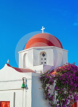 Church with a red roof in the town of Mykonos with Bougainvillea flowers