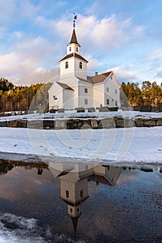 Church reflected in water, winter, snow and blue sky in Iveland Norway, vertical