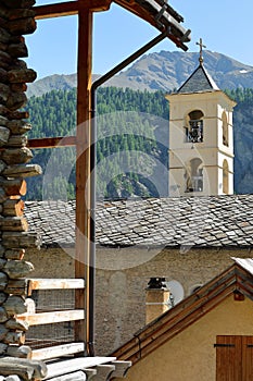 The church of Saint Veran with a traditional wooden house in the foreground and mountains in the background