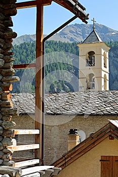 The church of Saint Veran with a traditional wooden house in the foreground and mountains in the background photo