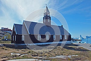 A church in small town of Ilulissat Greenland with a view to Disko Bay and icebergs