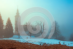 Church of St. John the Baptist by the Bohinj Lake in Ribcev Laz, Slovenia in foggy morning. 700 years old example of Slovenian