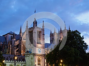 The Church of St Margaret with the Westminster Abbey in the background on Parliament Square, London all illuminated at dusk.