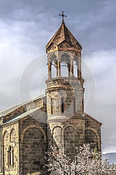 Church of St.Mesrop Mashtots with a cylindrical bell tower among flowering apricot trees