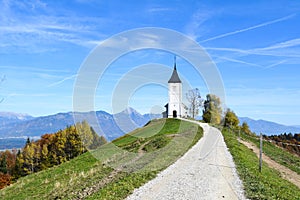 The church of St. Primoz in Slovenia near Jamnik with colorful autumn trees and blue sky