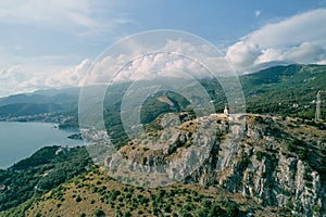 Church of St. Sava on a rocky mountain overlooking the green mountain range above the Bay of Kotor. Montenegro. Drone