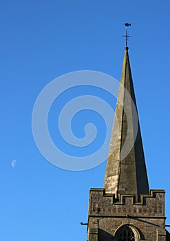 Church steeple and moon in blue sky