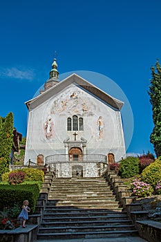 Church with steeple, paintings and child in city center of Conflans