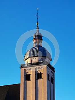 A church tower and at the end of the tower hangs a cross