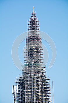 Church tower with scaffolding against blue sky