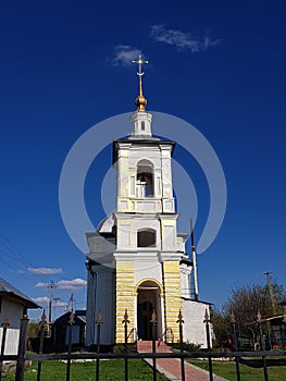 The church is white with a path of pink stone. The top of the church touched the obliquity in the sky. Around the green grass.