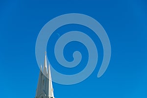 Churck steeple against a clear blue sky and the crescent moon