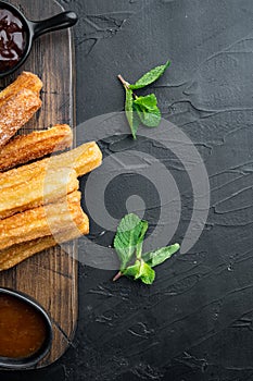 Churros with caramel Traditional Spanish cusine  on black background  top view flat lay with space for text  copyspace