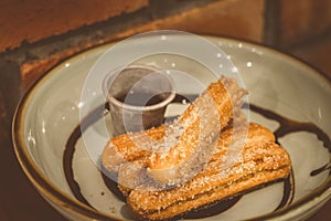 Churros Fried Spanish donuts x4 stacked and served with chocolate dip in a bowl