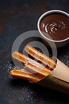 Churros in paper bag with sugar and chocolate sauce photo